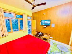 a bedroom with a red bed and a television at Grand view lodge and Restaurant Dharamshala - Partial Prepayment required to confirm booking in Dharamshala