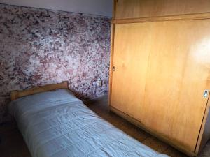 BillinghurstにあるHabitacion privada en Billinghurst, Gral San Martinのベッドルーム1室(ベッド1台付)、木製キャビネットが備わります。
