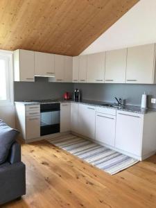 cocina con armarios blancos y techo de madera en Ballmoos Ferienwohnung en Gais