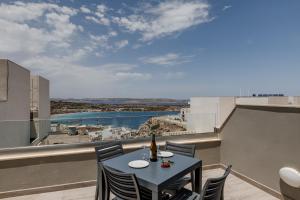 einen Tisch und Stühle auf einem Balkon mit Aussicht in der Unterkunft Lovely Penthouse In Mellieha-seaview in Mellieħa