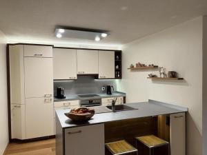 a kitchen with white cabinets and a bowl of fruit on a counter at Ferienwohnung Chäserruggblick mit Charme in Unterwasser