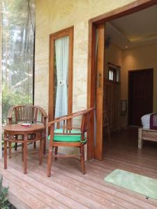 a room with two chairs and a table on a porch at Jungle Joglo in Tampaksiring