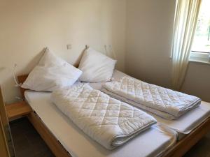a bed with white sheets and pillows on it at E21 Freistehendes Haus mit Garten und Deichblick in Butjadingen