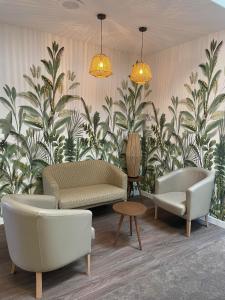 uma sala de estar com sofás, mesas e plantas em Logis Hôtel Lucotel em Lanvollon