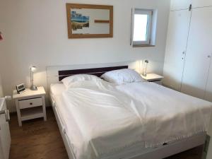 布特亚丁根E3 Haus mit Wintergarten, Kamin und Deichblick的卧室里有一张白色床和两个床头柜