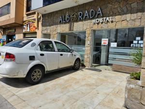une voiture blanche garée devant un magasin dans l'établissement alborada cuenca hospedaje, à Cuenca