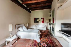 1 dormitorio con 1 cama blanca y TV en Villa Belcanto Mugello - Affitti Brevi Italia en Vicchio