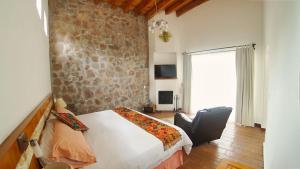 sypialnia z łóżkiem z krzesłem i kamienną ścianą w obiekcie Cabin Zarzamora Nature Retreat with amenities w mieście Zitácuaro