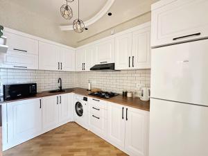 a white kitchen with white cabinets and a dishwasher at Panoramic City view Apartment with Playstation 5 in Baku