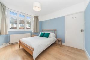 a bedroom with blue walls and a bed with green pillows at Pass the Keys Spacious Family Home in London in London