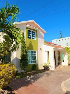 une maison jaune et blanche avec un palmier dans l'établissement Casa Coccoloba, Chetumal, Quintana Roo, à Chetumal