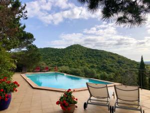 a swimming pool with two chairs and a mountain at Casa Matteu in Figari