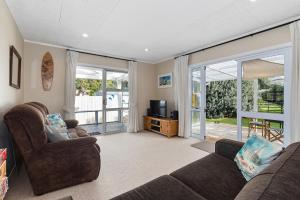 a living room with a couch and a tv and sliding glass doors at Teal Bay Treasure - Teal Bay Holiday Home in Whangaruru North