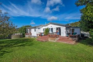 a white house with a picnic table on a lawn at Teal Bay Treasure - Teal Bay Holiday Home in Whangaruru North