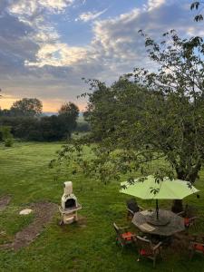 un tavolo con sedie e un ombrellone in un campo di Maison d'hôtes Petit Coin de Paradis a Moyon