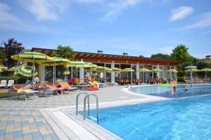 a pool with chairs and umbrellas and a resort at Villaggio Marco Polo in Bibione