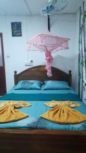 Una cama con sombrilla rosa y toallas. en KANTHI GUEST INN, en Trincomalee