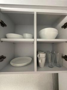a white cabinet with plates and bowls and other dishes at C&C Studio in San Juan