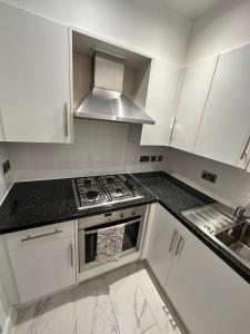 a kitchen with white cabinets and a stove top oven at London Waterloo Moments away in London