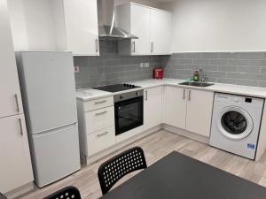cocina con armarios blancos, lavadora y secadora en Modern Central London Room Zone1, en Londres