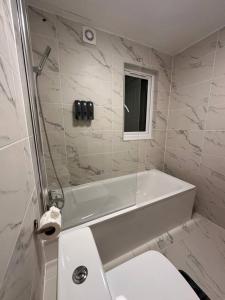 a white bathroom with a tub and a toilet at London Vauxhall - Victoria room in London