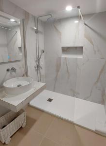 La salle de bains blanche est pourvue d'un lavabo et d'une douche. dans l'établissement Apartamentos Herdade dos Salgados - Vila das Lagoas, à Albufeira