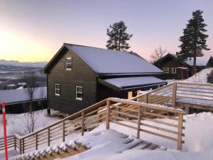 a house covered in snow with a wooden fence at Cabin - Målselv fjellandsby in Bergset