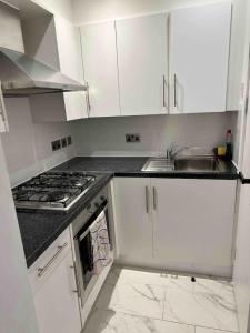 a kitchen with white cabinets and a sink and a stove at Buckingham Palace 15minutes away in London