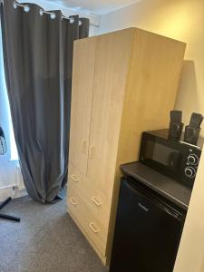 a large wooden cabinet with a microwave next to it at Buckingham Palace 15minutes away in London