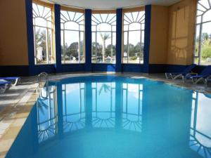 una piscina con agua azul en un edificio con ventanas en TMK L'Atrium Yasmine Hammamet, en Hammamet