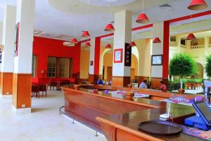 een restaurant met tafels en stoelen en rode muren bij TMK L'Atrium Yasmine Hammamet in Hammamet