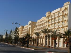 a street in front of a large building with palm trees at TMK L'Atrium Yasmine Hammamet in Hammamet