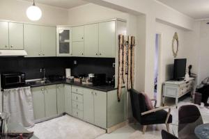 a kitchen with white cabinets and a living room at Lucato apartment in Florina