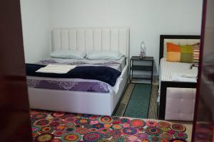 a bedroom with a white bed and a colorful rug at SuperPanorama GuestHouse in Kukës