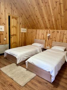two beds in a room with wooden walls at Shtil in Kyiv
