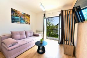 sala de estar con sofá púrpura y puerta corredera de cristal en Apartments Patar, en Grabovac
