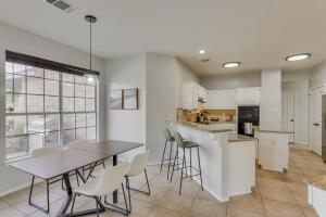 uma cozinha com armários brancos e uma mesa e cadeiras em Amazing Modern Spacious Home with Pool em Rowlett