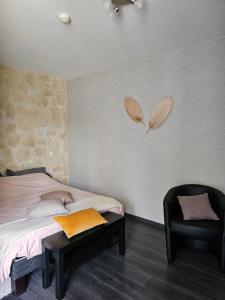 a bedroom with a bed and a black chair at B&B Soissons L'Arthome chambres d'hôtes 