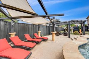 eine Terrasse mit roten Stühlen und einem Pool in der Unterkunft Creekside Charm w Pool Backyard Oasis Patio in Plano