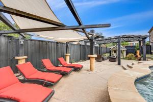 a patio with red chairs and a swimming pool at Creekside Charm w Pool Backyard Oasis Patio in Plano