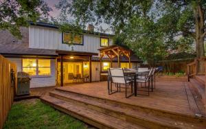una terraza de madera con mesa y sillas. en Stunning Modern Dream Home w Pool Grill Foosball, en Houston