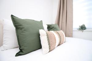 a bed with green and white pillows on it at 5 bedroom sleeps 10 | City Centre Newport in Newport