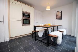 eine Küche mit einem Tisch und Stühlen mit weißen Schränken in der Unterkunft 5 bedroom sleeps 10 | City Centre Newport in Newport