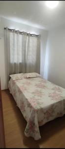 a bedroom with a bed with a floral blanket on it at Apartamento exclusivo, próximo a UFMS in Campo Grande