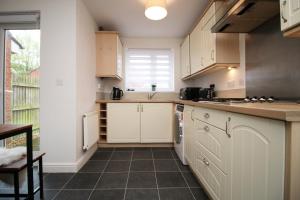 a kitchen with white cabinets and a tile floor at 5 bedroom sleeps 10 | City Centre Newport in Newport