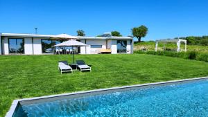a house with a lawn with two chairs and a swimming pool at MONTE DA FIFAS Alentejo, Montargil in Montargil