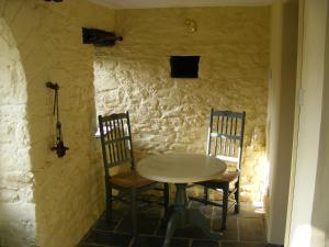 a table and chairs in a room with a stone wall at The Coach House New Quay in Cross Inn