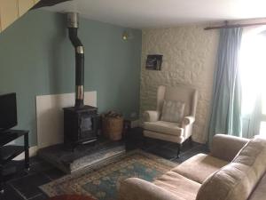 a living room with a stove and a couch and a chair at The Coach House New Quay in Cross Inn