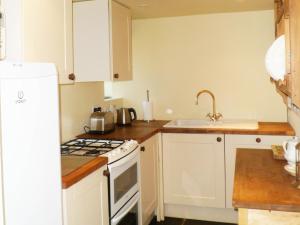a kitchen with a white stove top oven next to a sink at The Coach House New Quay in Cross Inn