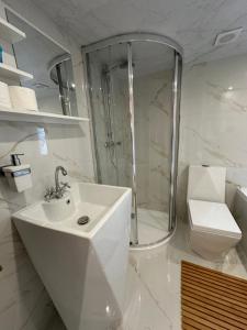 a white bathroom with a shower and a sink at Domki Nad Sanem Bachórzec in Dubiecko